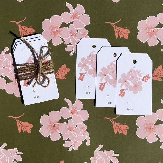 gift tag 3 pack with olive blossom design, shown tied with twine laying on coordinating wrapping paper