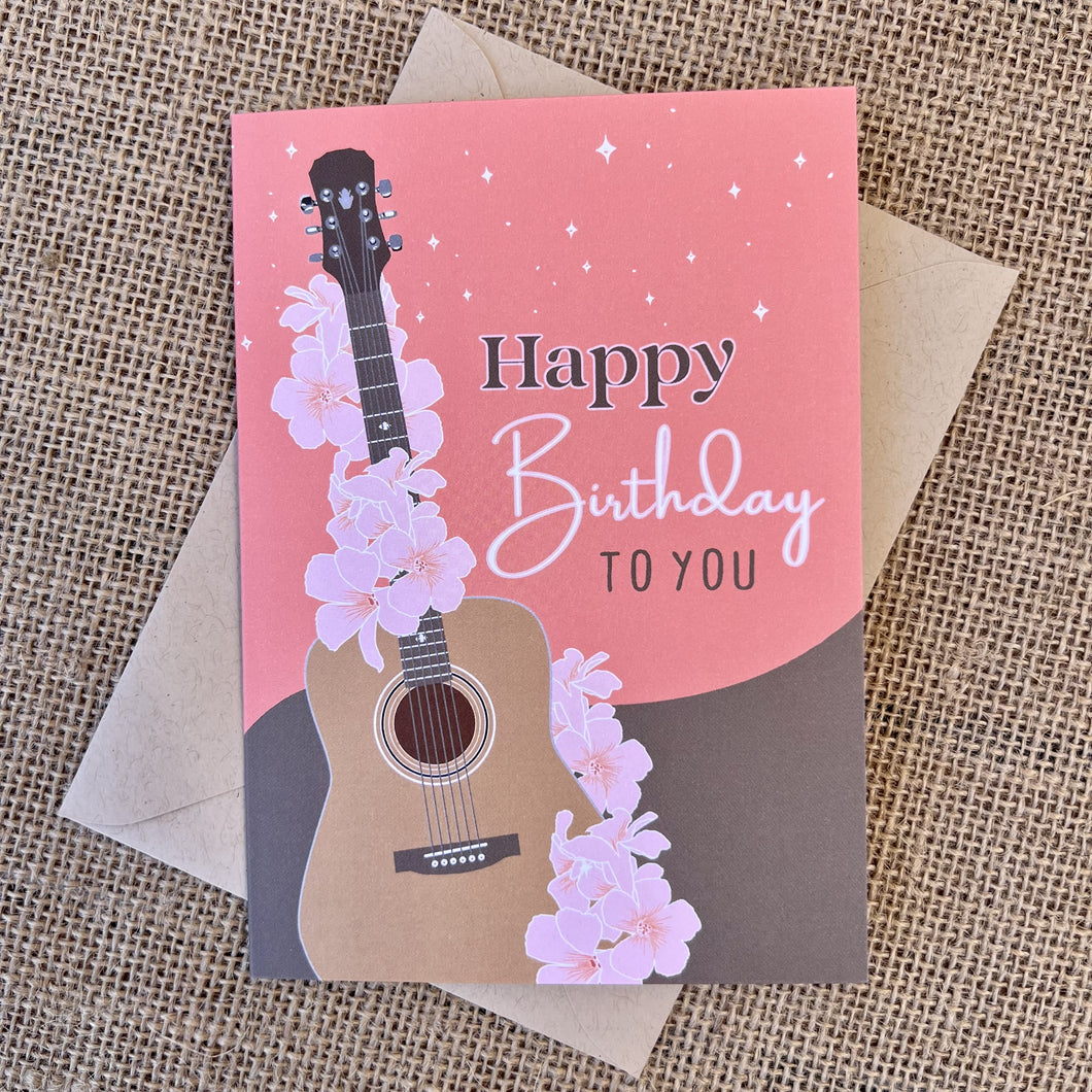 Greeting card with pink & brown background and pink floral guitar illustration, text reading 