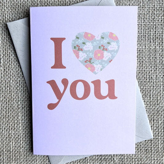 Greeting card with pink background and "I love you" written with a heart filled with a floral pattern