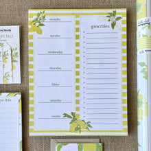 Load image into Gallery viewer, notepad with yellow and white stripes and lemon tree illustrations, with boxes for days of the week in a column on the left and a column for a grocery list on the right
