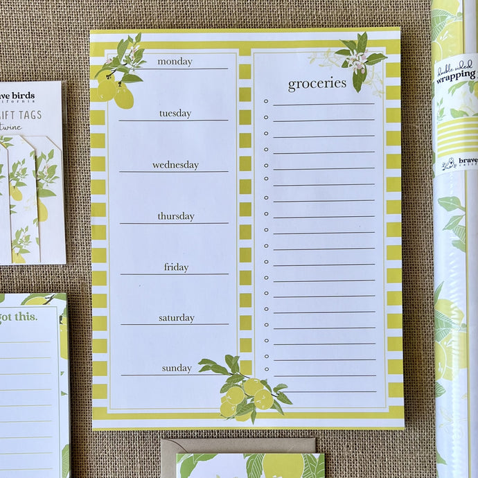 notepad with yellow and white stripes and lemon tree illustrations, with boxes for days of the week in a column on the left and a column for a grocery list on the right