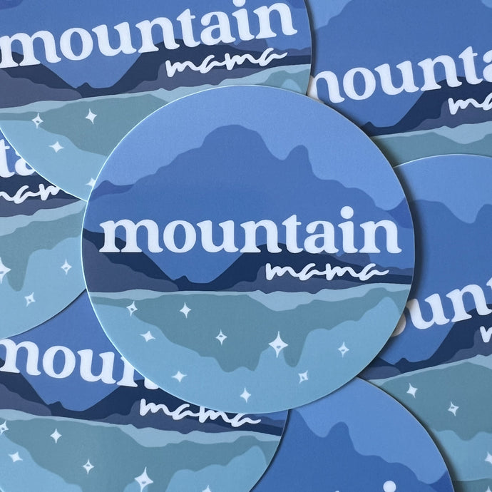 pile of circular stickers with a mountain illustration in shades of blue and text reading mountain mama