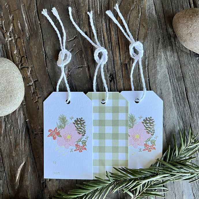 Set of three TO/FROM gift tags with floral pinecone illustrations on the front and allover green gingham plaid print on the back. Each tag has white cotton twine laced through a hole at the top.