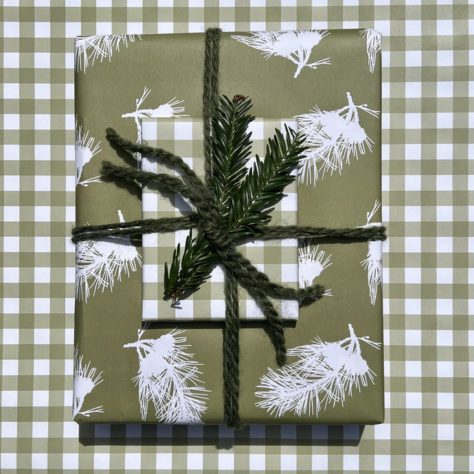 Giftwrapped package with two boxes, one in a green pine branch pattern, one in a green gingham plaid