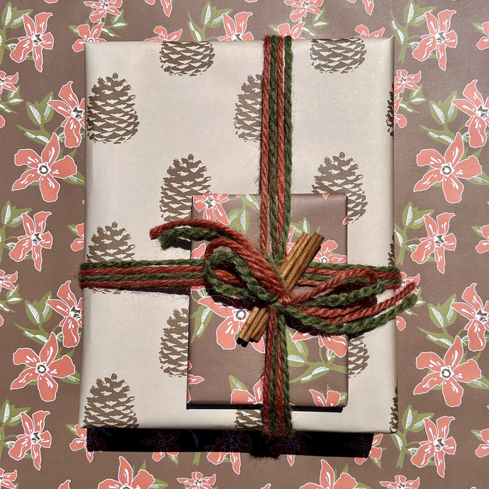 Giftwrapped package with two boxes, one in a khaki and brown pinecone pattern, one in a red and brown floral print