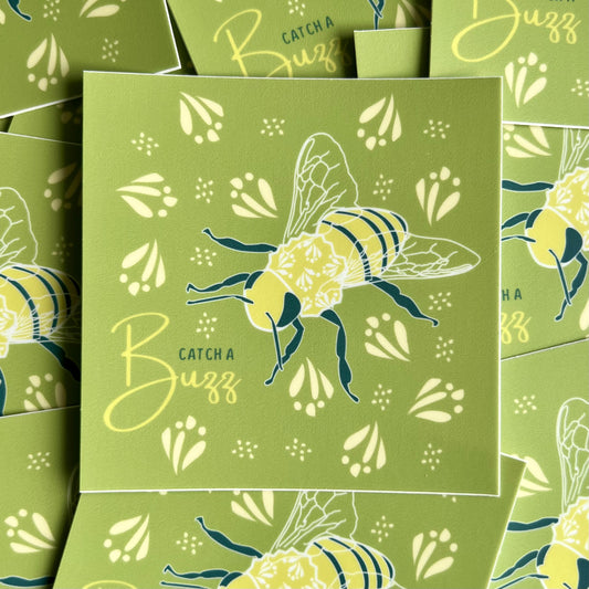 Green square sticker with a yellow bee illustration and the words "catch a buzz" in blue & yellow ink